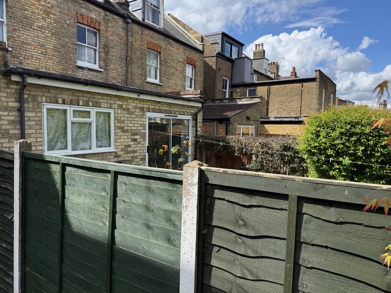 Rear gardens viewed across the terrace, showing the full-width flat-roof extension at No. 89 against neighbouring rooflines