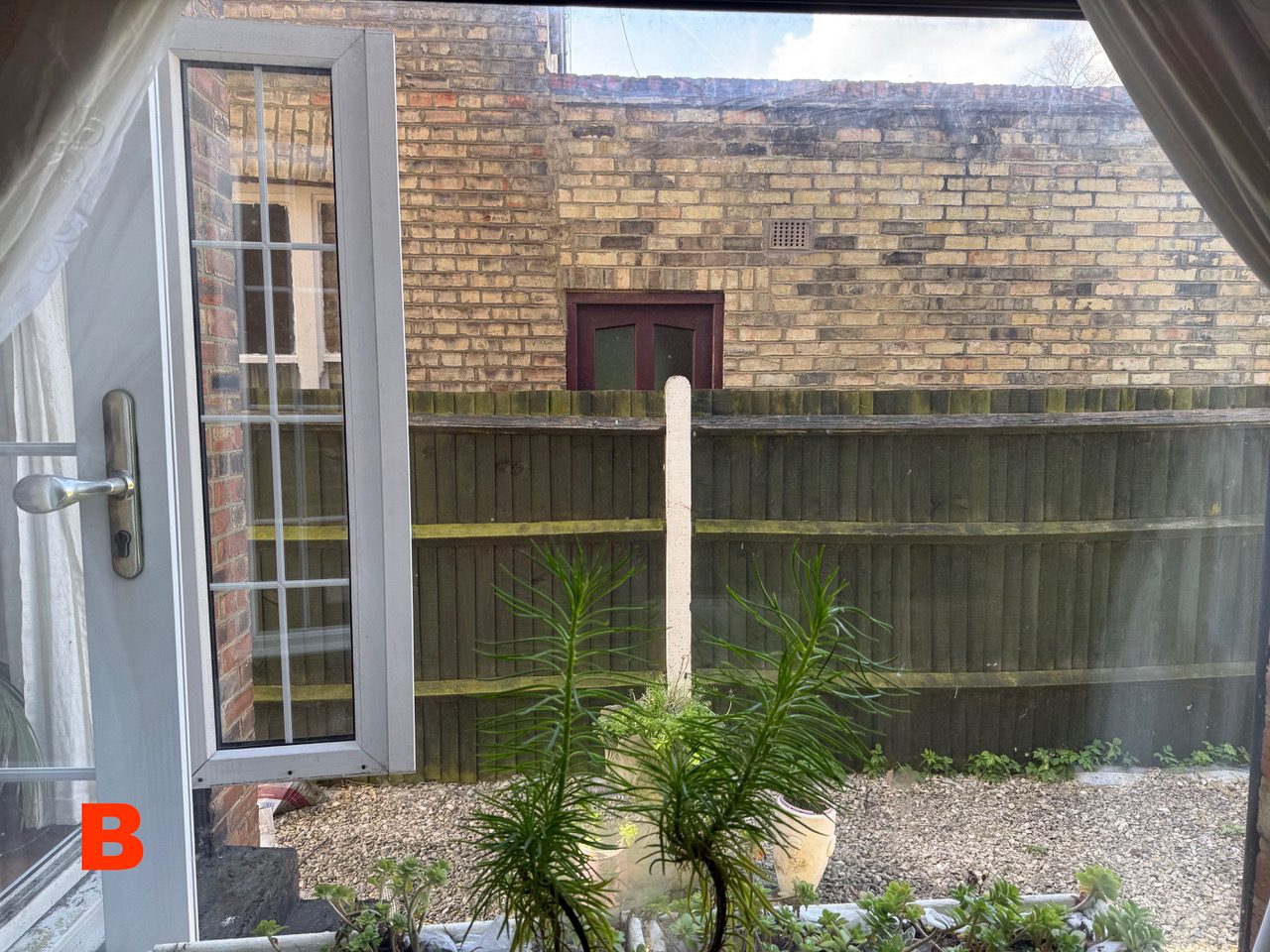 View out of window B at [REDACTED], looking directly onto the brick side wall of No. 89